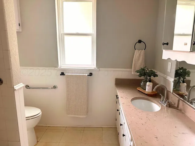 a bathroom with a granite countertop sink a toilet and a mirror