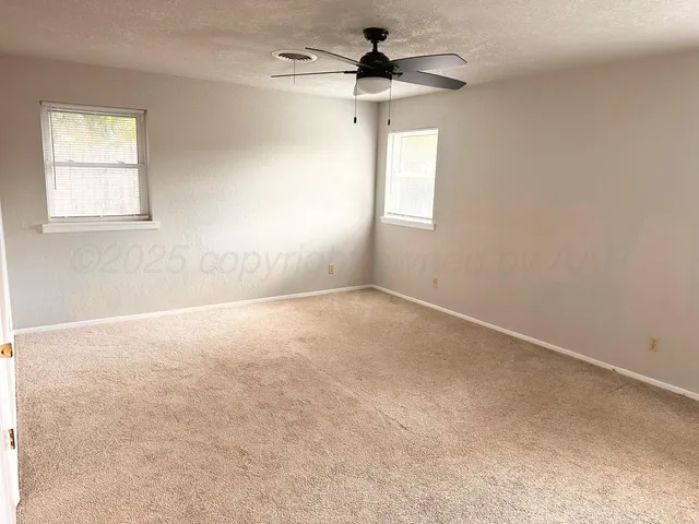 an empty room with windows and fan