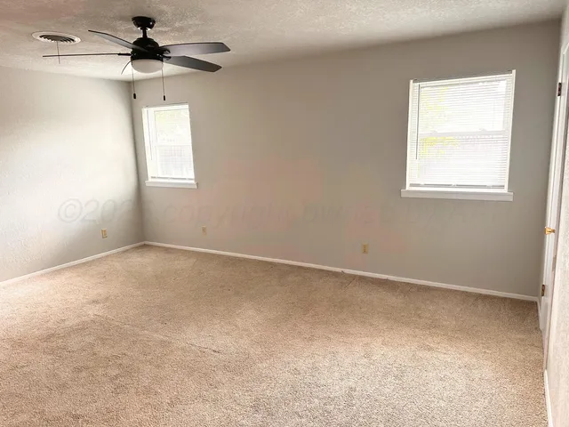 an empty room with a window and a ceiling fan