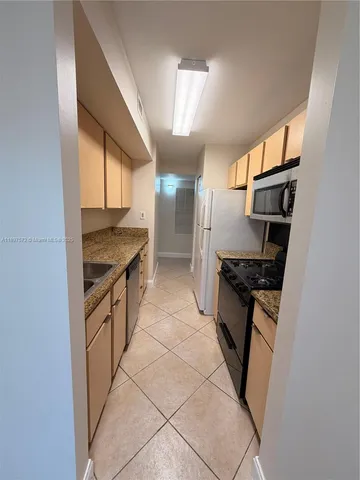 a kitchen with granite countertop a sink stove and refrigerator