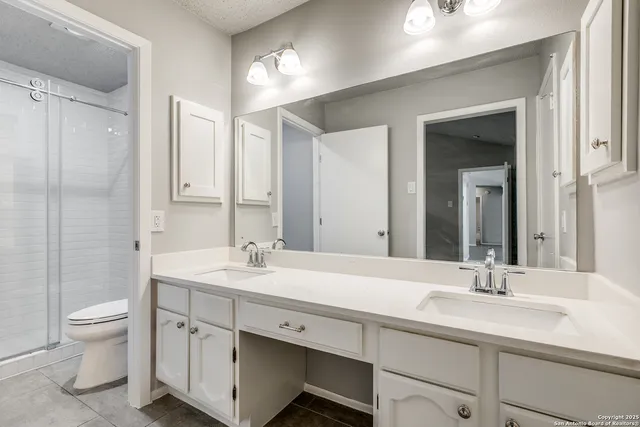 a bathroom with a double vanity sink toilet and a mirror