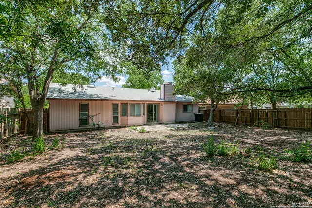 a view of a house with a yard tree and wooden fence