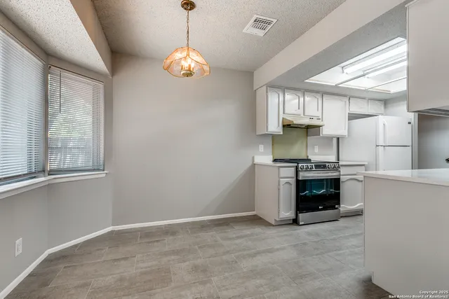 a kitchen with stainless steel appliances a stove a sink and a chandelier