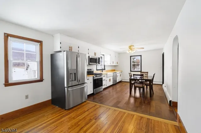 a kitchen with granite countertop a refrigerator a stove a dining table and chairs with wooden floor