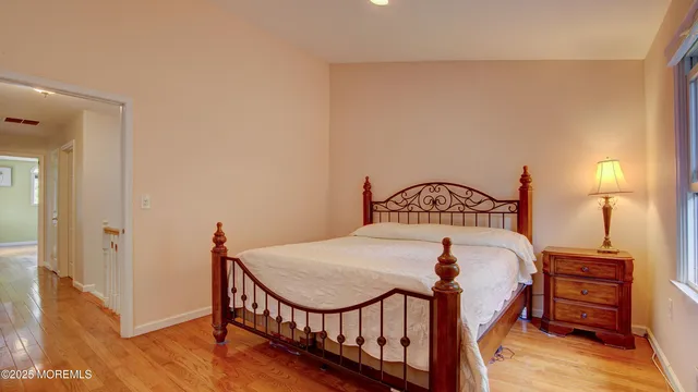 a bedroom with a bed a dresser and wooden floor