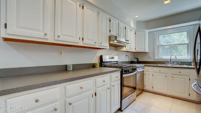 a kitchen with granite countertop white cabinets white stainless steel appliances and sink