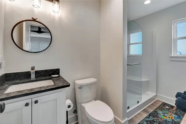 a bathroom with a granite countertop toilet sink and mirror