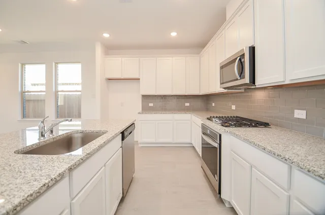 a kitchen with granite countertop a sink and white cabinets