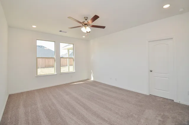 an empty room with windows and fan