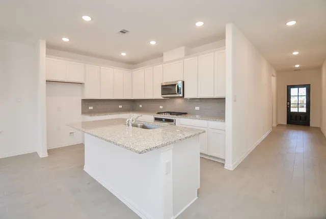 a kitchen with a sink stove a refrigerator and white cabinets with wooden floor