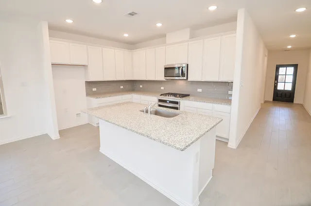 a kitchen with stainless steel appliances granite countertop a sink stove and refrigerator