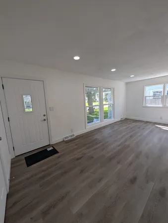 an empty room with wooden floor and windows