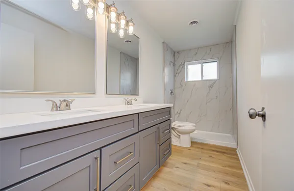 a bathroom with a granite countertop sink a toilet and a mirror