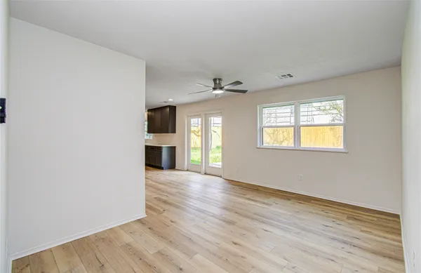 a view of an empty room with wooden floor and a window