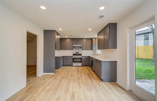 a kitchen with stainless steel appliances kitchen island granite countertop a refrigerator and a sink