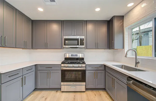 a kitchen with cabinets stainless steel appliances and sink