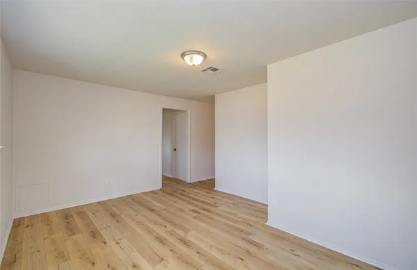 a view of an empty room with wooden floor and closet