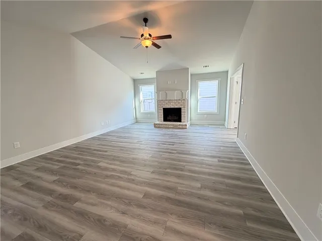 a view of an empty room with a fireplace and a chandelier fan