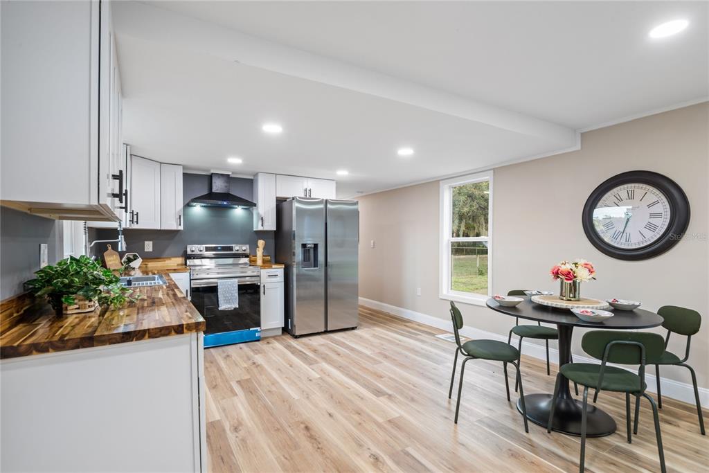6455 West Cardinal Street Homosassa, FL 34446 - Photo 20 of 38 a kitchen with granite countertop a stove a sink dishwasher a dining table and chairs with wooden floor