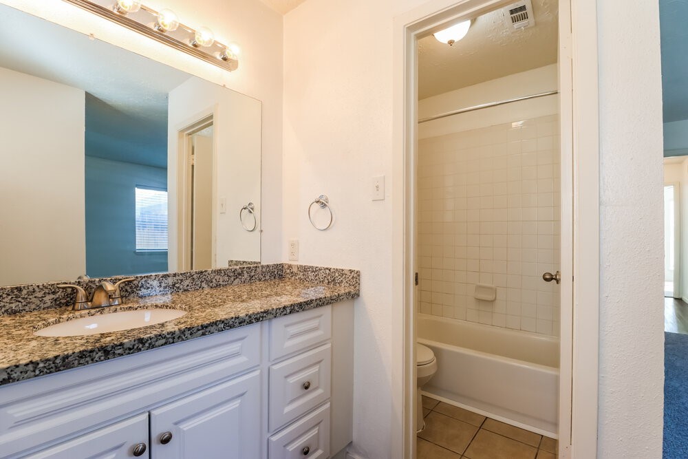 13411 Reads Court Houston, TX 77015 - Photo 11 of 16 a bathroom with a granite countertop sink and a mirror