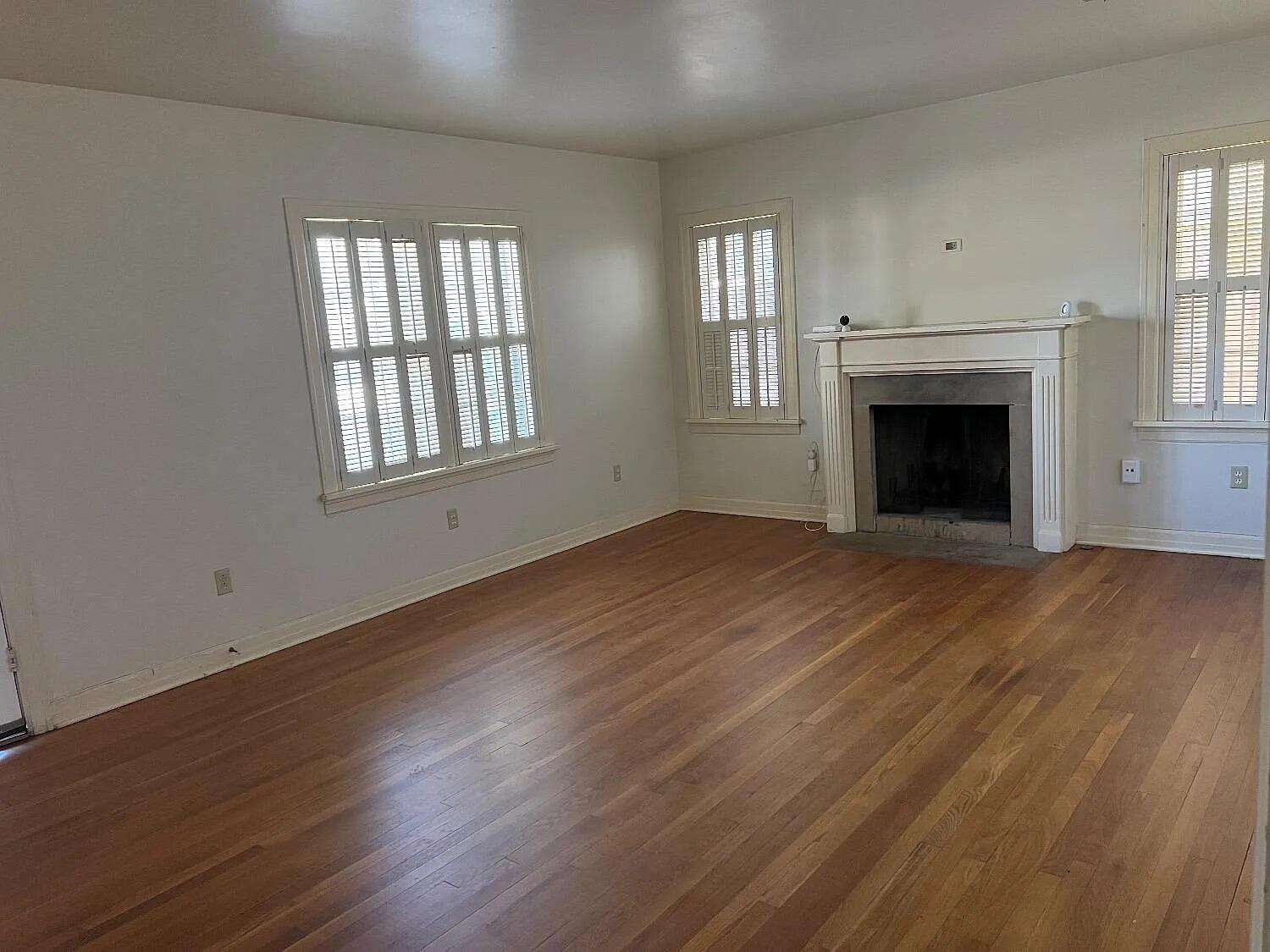 3013 22nd Street Lubbock, TX 79410 - Photo 7 of 9 an empty room with wooden floor fireplace and windows