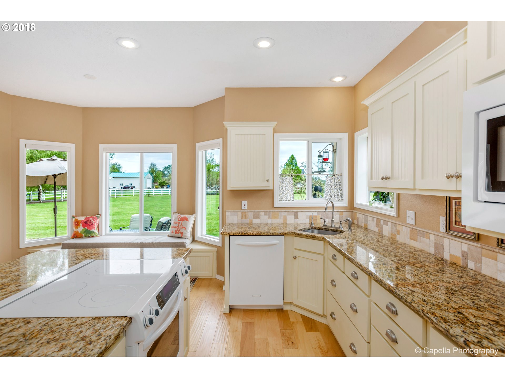 11675 Hazelgreen Road Northeast Silverton, OR 97381 - Photo 10 of 32 a kitchen with kitchen island a sink a stove a refrigerator cabinets and a large window