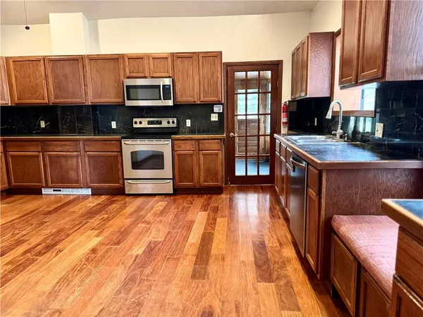 a kitchen with stainless steel appliances granite countertop a stove a sink and a microwave