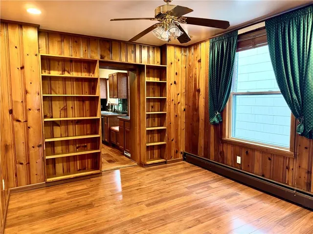 a view of an empty room with a window and wooden floor
