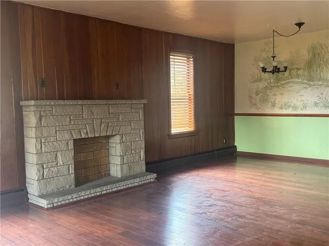 an empty room with wooden floor a fireplace and windows