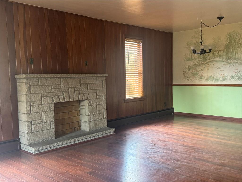 426 Beaver Street Wampum, PA 16157 - Photo 4 of 23 an empty room with wooden floor a fireplace and windows