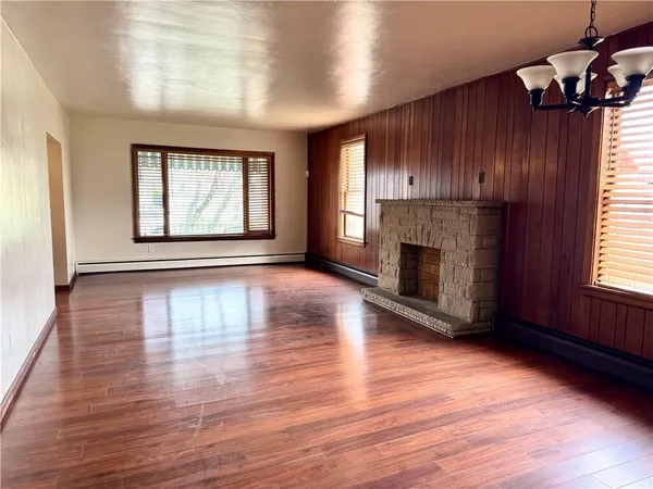 an empty room with wooden floor fireplace and windows