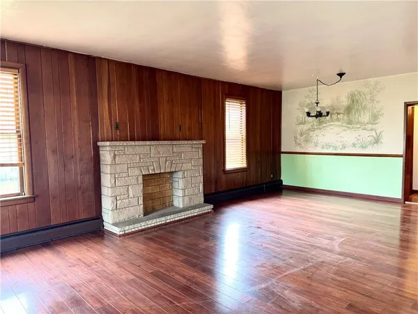 an empty room with wooden floor a fireplace and windows