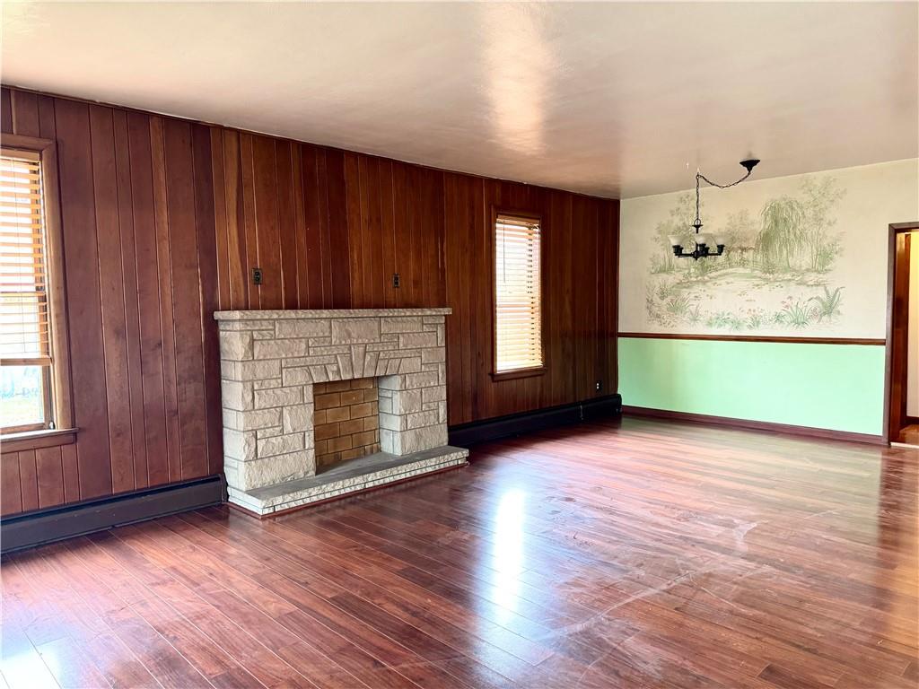 426 Beaver Street Wampum, PA 16157 - Photo 6 of 23 an empty room with wooden floor a fireplace and windows