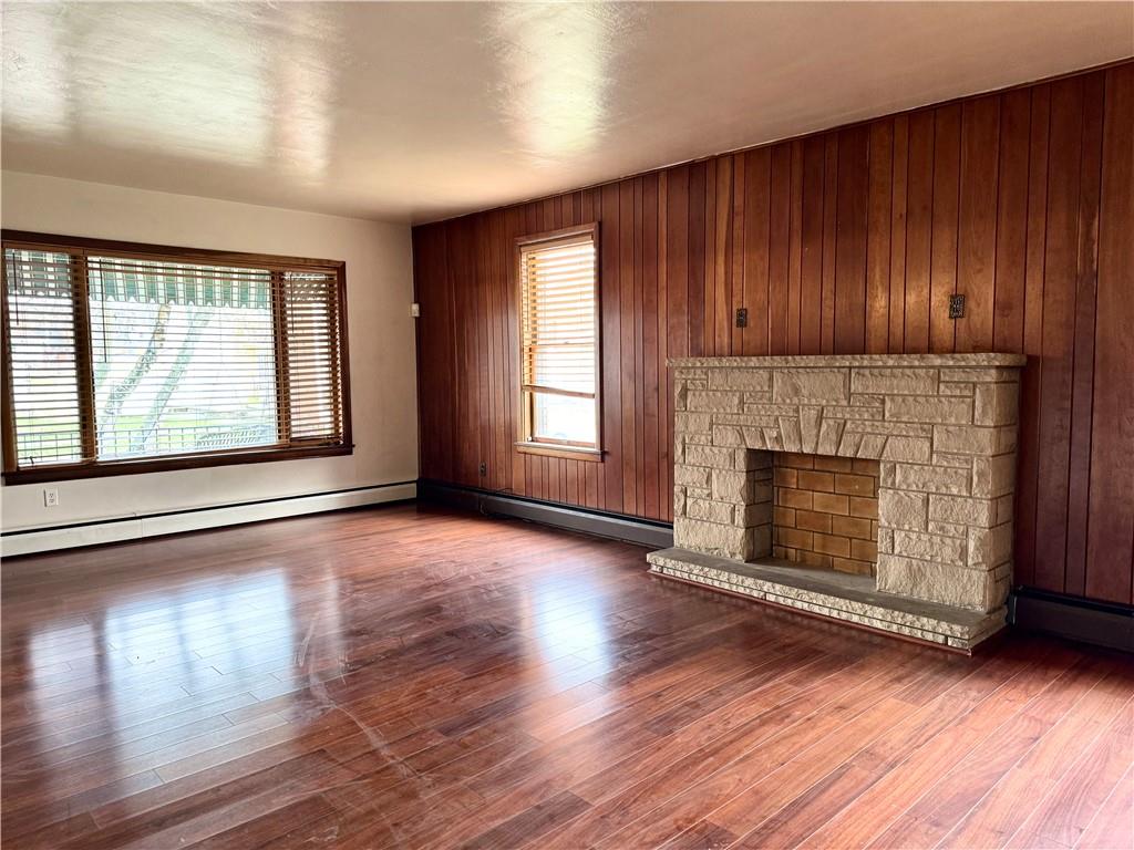 426 Beaver Street Wampum, PA 16157 - Photo 7 of 23 an empty room with wooden floor fireplace and windows