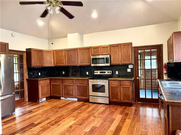 a large kitchen with stainless steel appliances granite countertop a stove and cabinets