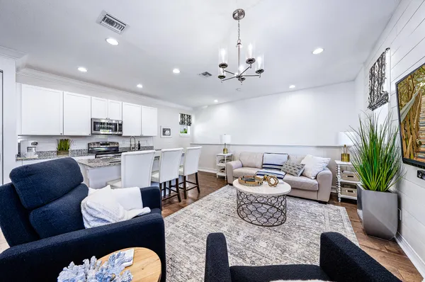 a living room with furniture kitchen view and a chandelier