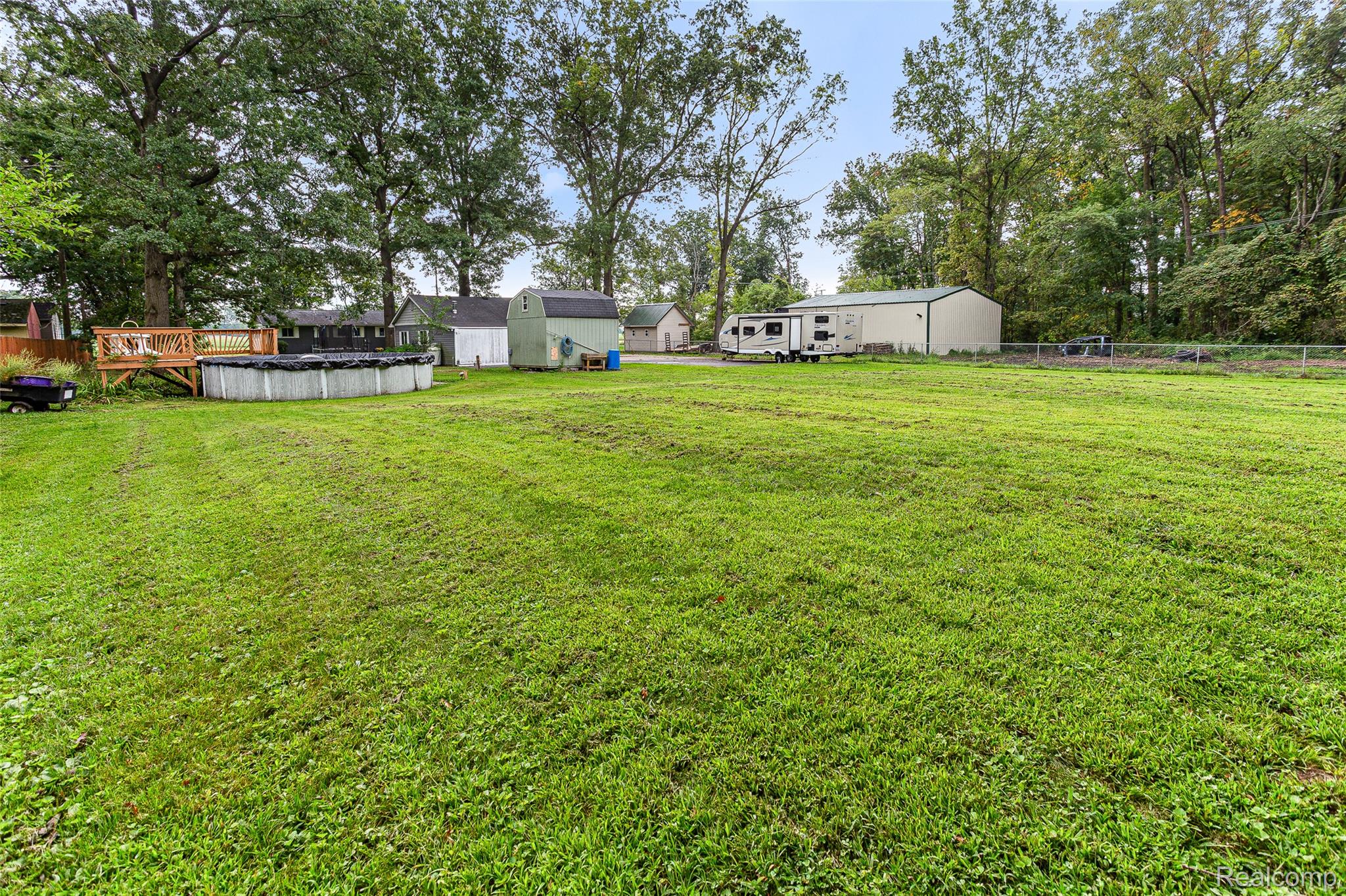 9561 Exeter Road Carleton, MI 48117 - Photo 45 of 46 Expansive green lawn with mature trees, above-ground pool, and wood deck
