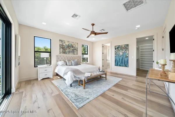 a spacious bedroom with a large bed a chandelier and windows