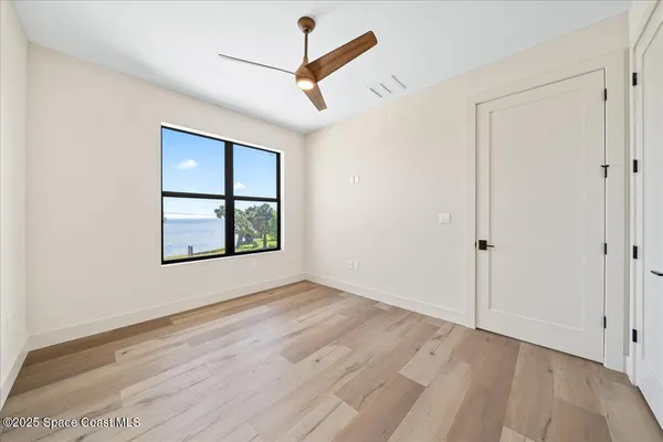 an empty room with wooden floor chandelier and windows