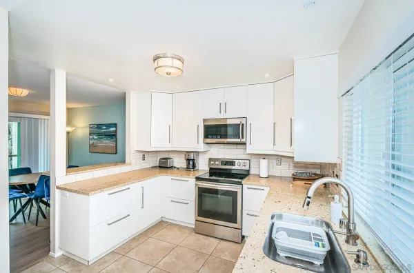 a kitchen with a sink white cabinets and white appliances