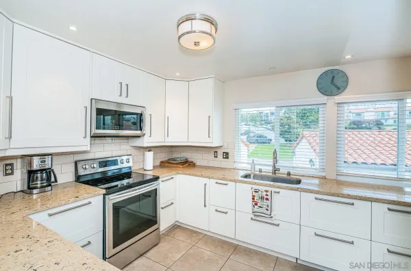 a kitchen with granite countertop a stove sink and microwave