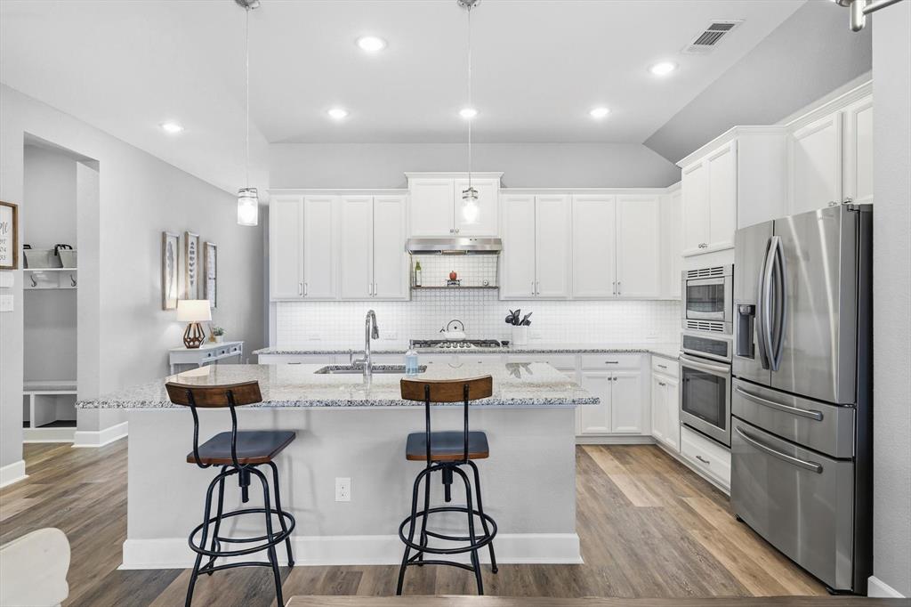 1701 Shetland Road Aubrey, TX 76227 - Photo 4 of 31 a kitchen with stainless steel appliances kitchen island granite countertop a refrigerator and a stove top oven