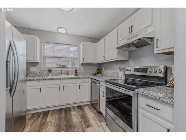 a kitchen with granite countertop a stove sink and refrigerator