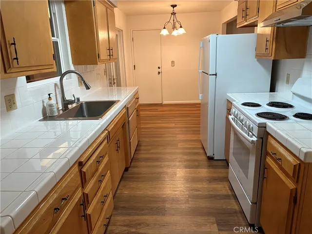 a kitchen with stainless steel appliances granite countertop a sink a stove and a wooden floors