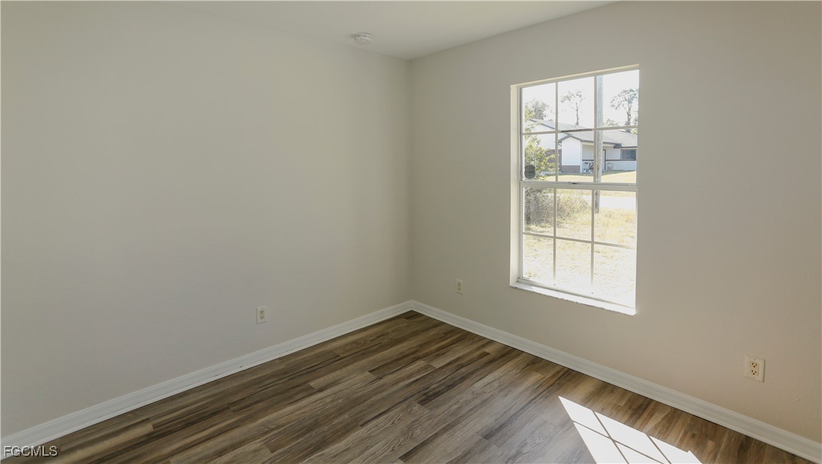 4612 25th Street Southwest Lehigh Acres, FL 33973 - Photo 13 of 15 an empty room with wooden floor and windows