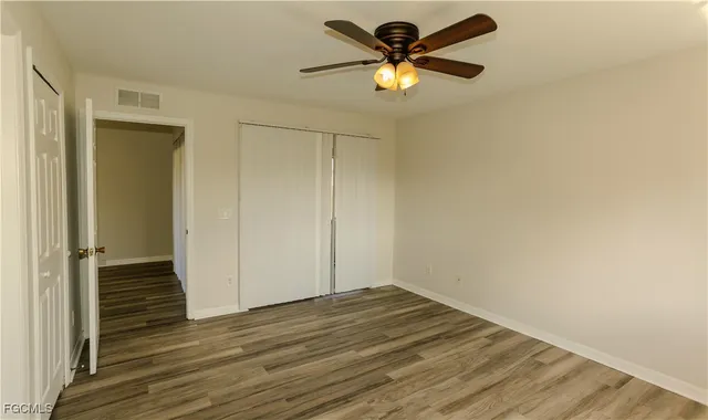 an empty room with wooden floor and a ceiling fan