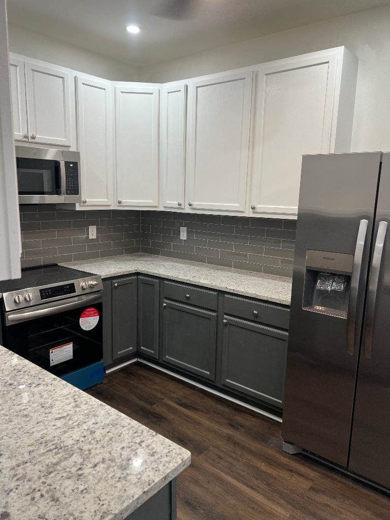 56 South Sanga Road Cordova, TN 38018 - Photo 12 of 26 Two tone kitchen featuring two tone cabinets, stainless steel appliances, dark wood-style floors, light stone countertops, and backsplash