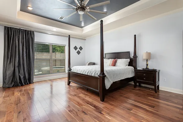 a bedroom with a bed a large window and wooden floor