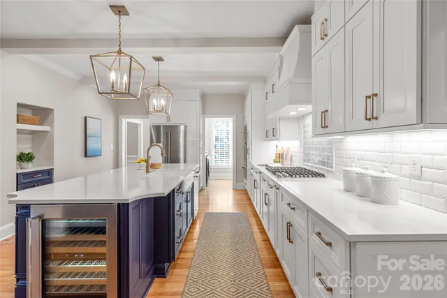 a kitchen with stainless steel appliances granite countertop a sink dishwasher stove and white cabinets with wooden floor