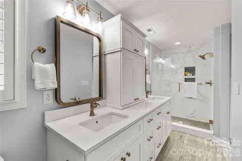 a bathroom with a double vanity sink mirror and shower